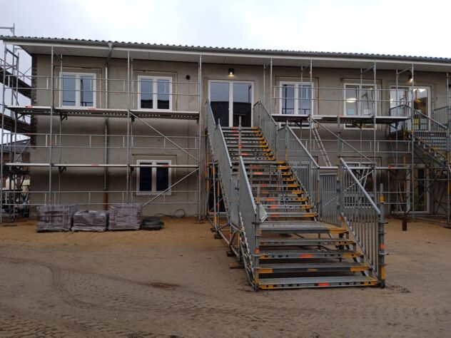 Außenansicht der noch unfertigen Kita Wirbelwind. Man sieht Baugerüste und unfertige Fassaden.